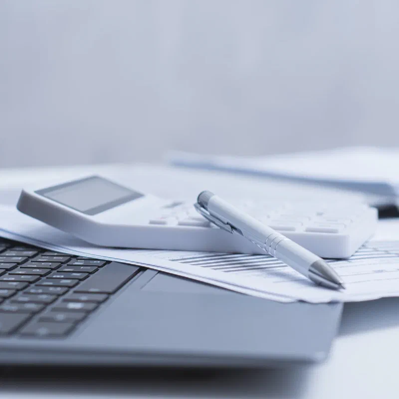 Ordinateur portable, calculatrice, stylo et documents comptables sur un bureau